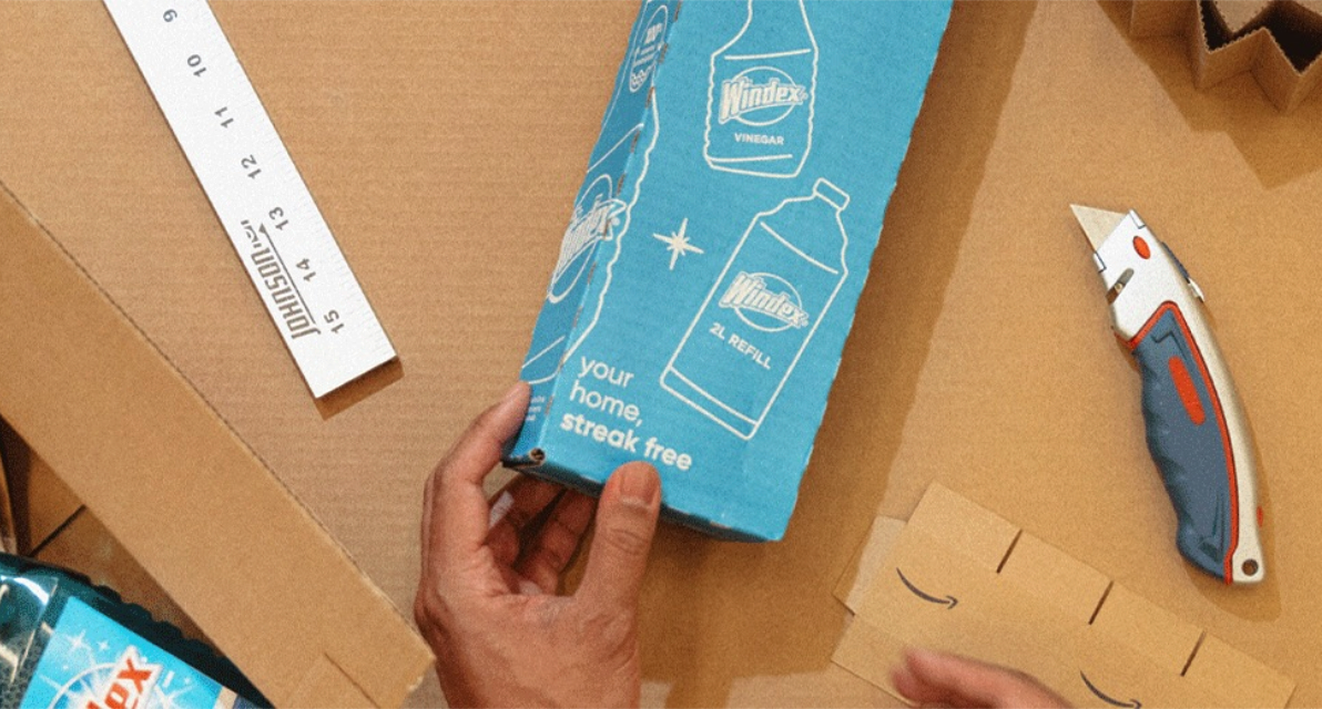 Hands on a table with a blue package, ruler, and box cutter. 