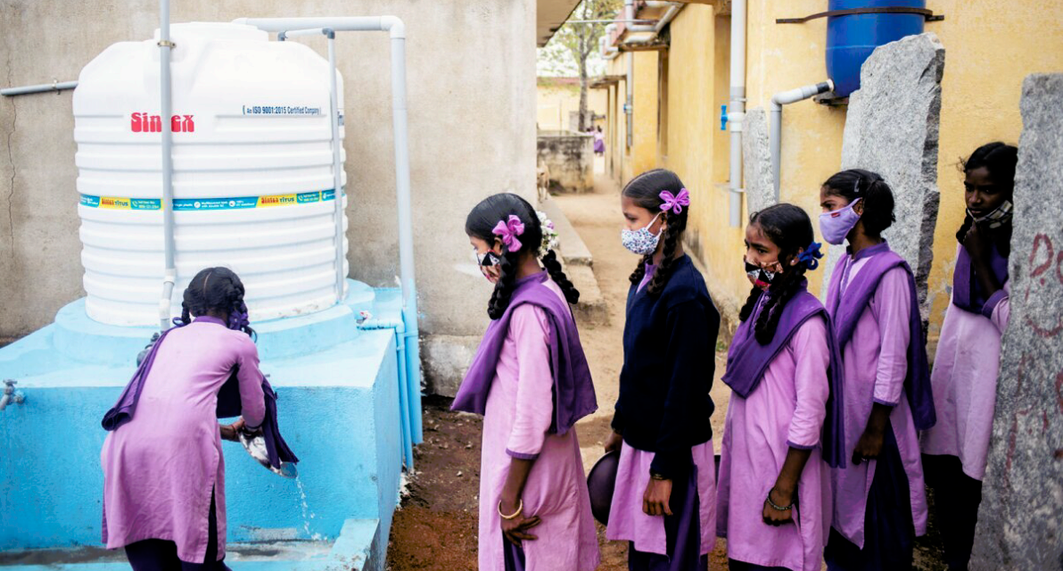 People gather in line at a handwashing station. 