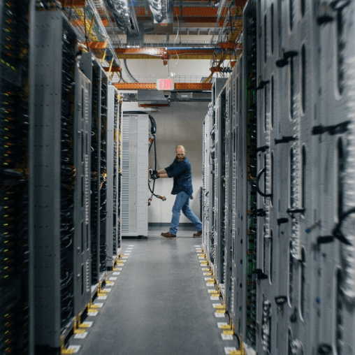 A person walks down an aisle in a data center. 