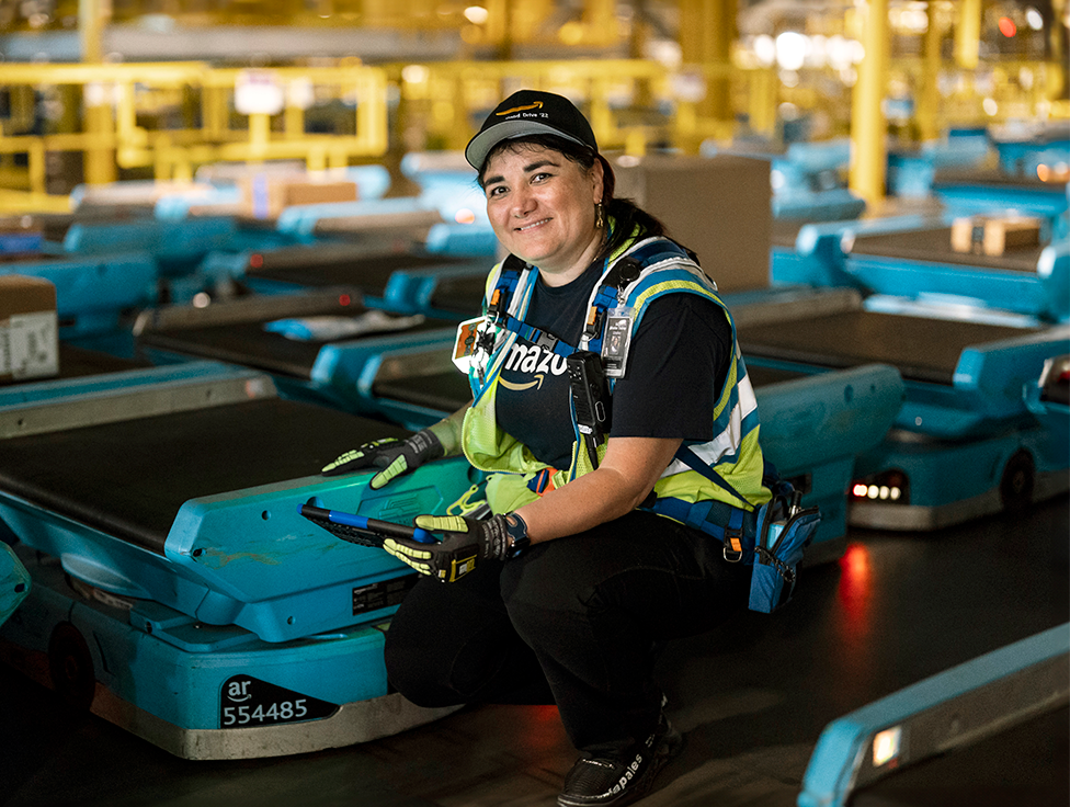 A person crouches smiling next to a machine.