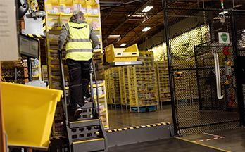 A person wearing a brightly colored safety vest climbs a ladder.