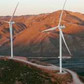 Wind power installation with two large turbines in the foreground on a hillside.
