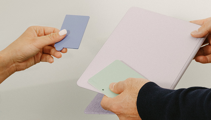 Hands holding samples of fabric materials.