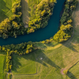 Three people stand smiling in front of a green graphic background. 