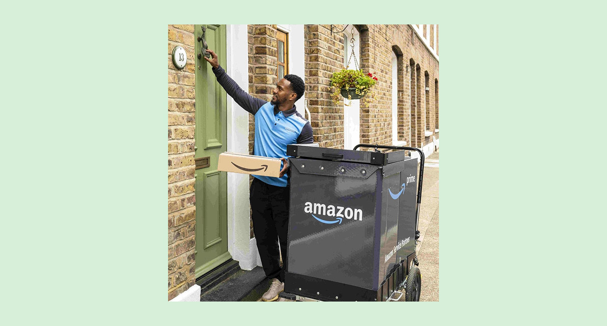A person holding a package knocks on the door of a brick building. 