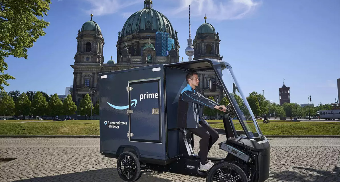 A person drives a delivery cart in front of an ornate building. 