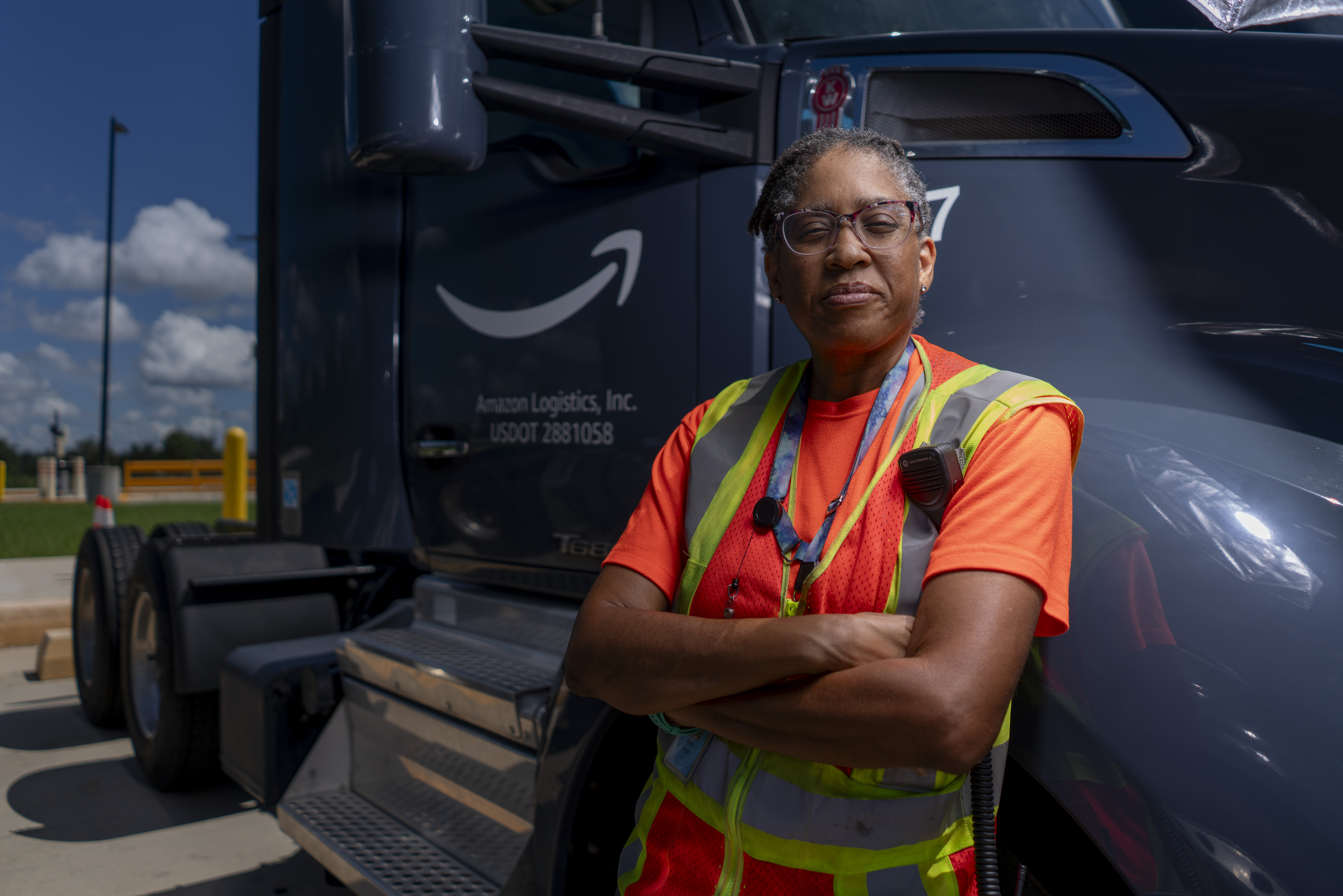 A person stands with crossed arms next to a truck.