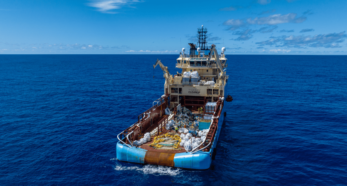 An aerial view of trash on the deck of a large ship with The Ocean Cleanup logo.