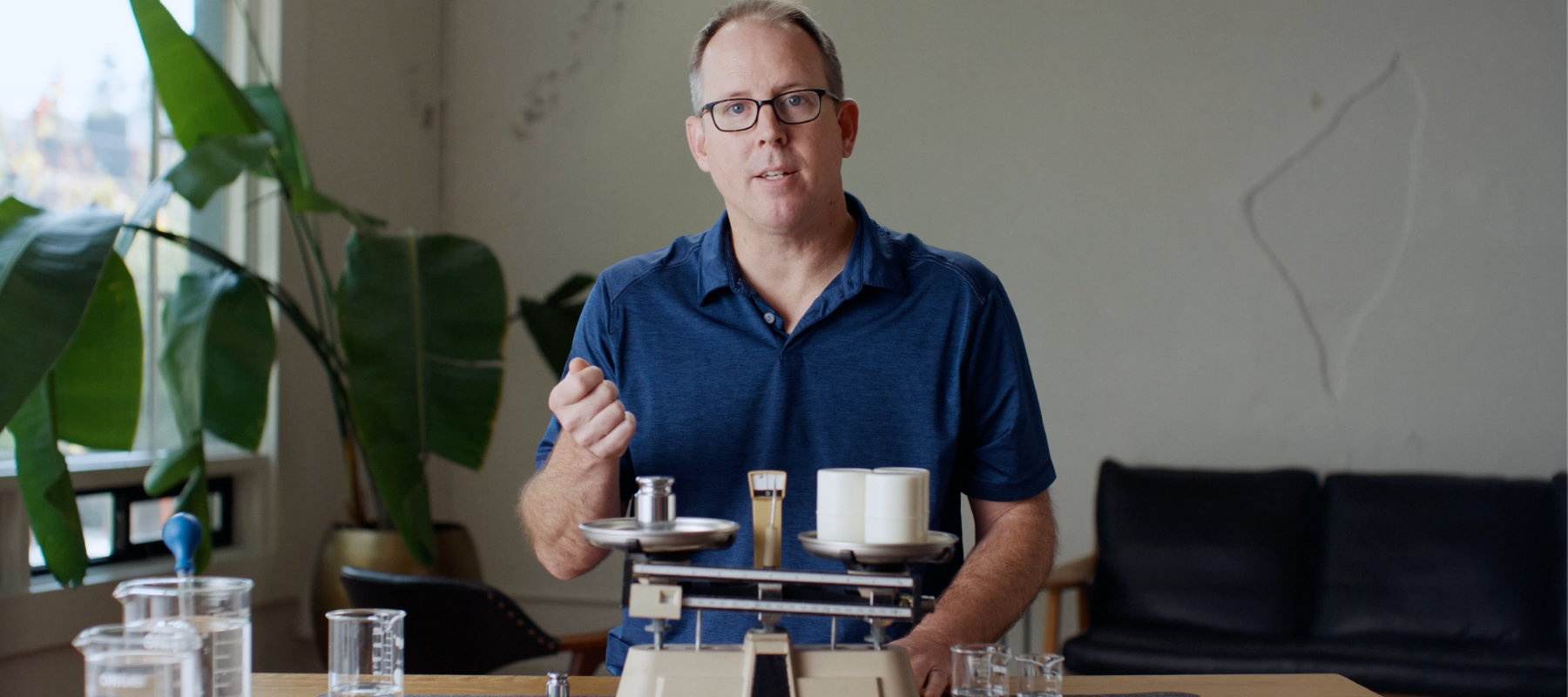 A person talking with a scale and scientific equipment in front of them.